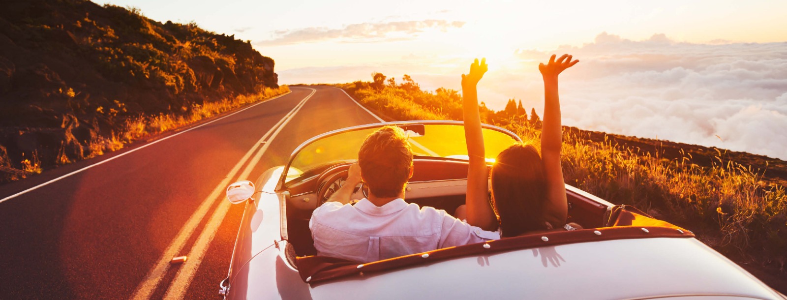 Couple driving in convertible on sunny road down the coast